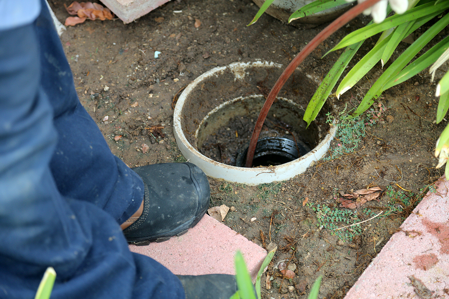 Sewer cleaning. A plumber uses a sewer snake to clean blockage i Sewer cleaning. A plumber uses a sewer snake to clean blockage in a sewer line.