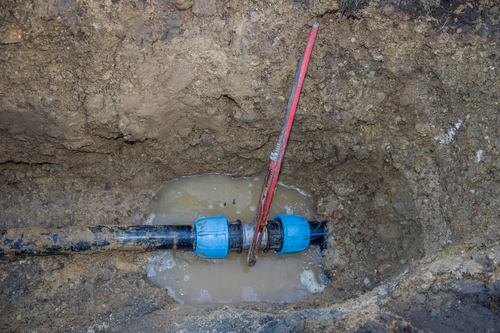 broken pvc pipe in trench with wrench leaks water